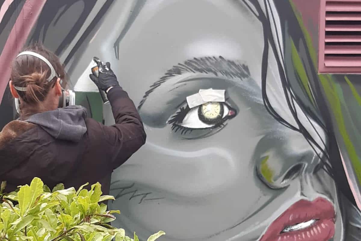 Zunächst grundierte Bernad die Blanko-Wand und skizzierte einen Raben und eine Frau auf die blassrosa Mauer. Anschließend besprühte er in seinem Style die Flächen und Konturen.