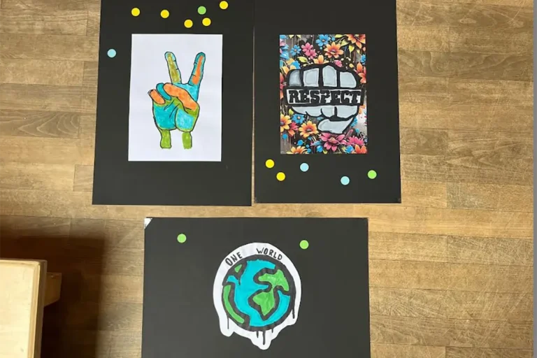 Gemalte Schülerentwürfe auf schwarzem Tonpapier mit Respekt-Schriftzügen, Peace-Zeichen und Friedenstauben