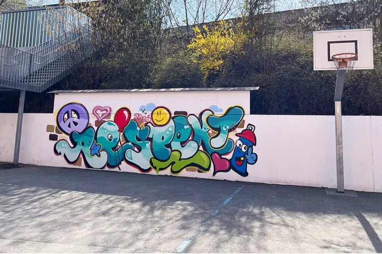 Fertiges Graffiti mit buntem Respekt-Schriftzug, Peace-Zeichen und Sprühdosen-Figur auf der Pausenhofwand der Pestalozzischule Leonberg